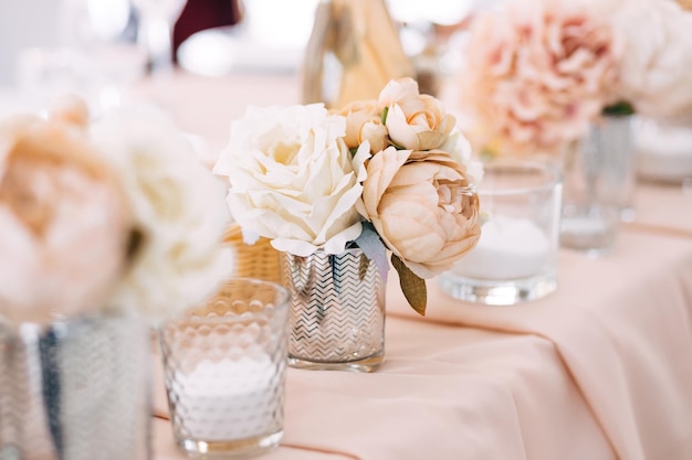Bankettafel perzikkleurig tafelkleed de tafel is gedecoreerd met composities gedecoreerd met servetten en bloemen in vazen