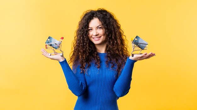 Banking service. Cashless society. Electronic payment. Cheerful young lady holding miniature shopping carts with credit cards in.