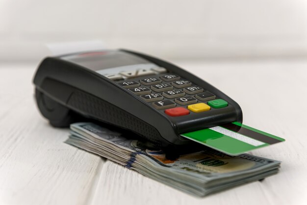 Banking terminal with green credit card and dollar