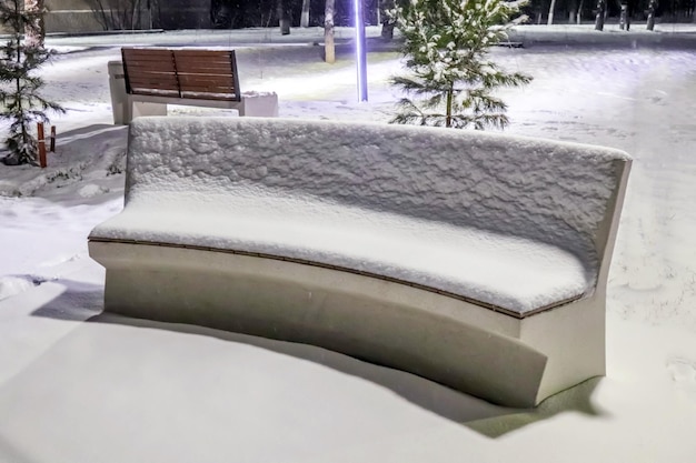 Bankje in de sneeuw in het stadspark 's nachts in de winter