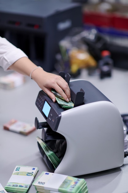 Bankmedewerkers gebruiken een geldtelmachine tijdens het sorteren en tellen van papieren bankbiljetten in een bankkluis. Grote hoeveelheden geld op de bank