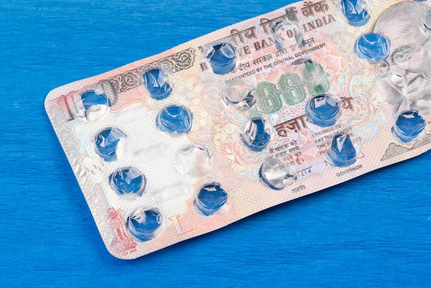 Banknote 1000 Indian rupees on an empty blister pack of tablets blue background