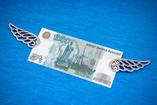 写真 青色の背景に装飾的な銀の翼を持つ紙幣 1000 ロシア ルーブル