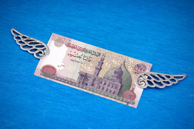 Photo banknote 200 egyptian pounds with decorative silver wings on a blue background