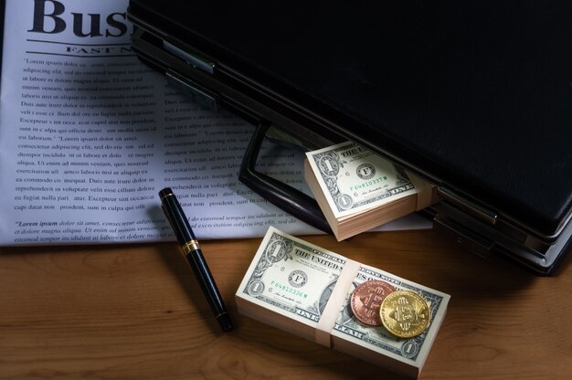 Banknote in briefcase, a pen, Put on a business newspaper and Bitcoins put on banknote.