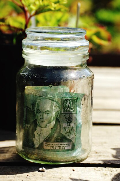 Photo banknote in jar on wooden table