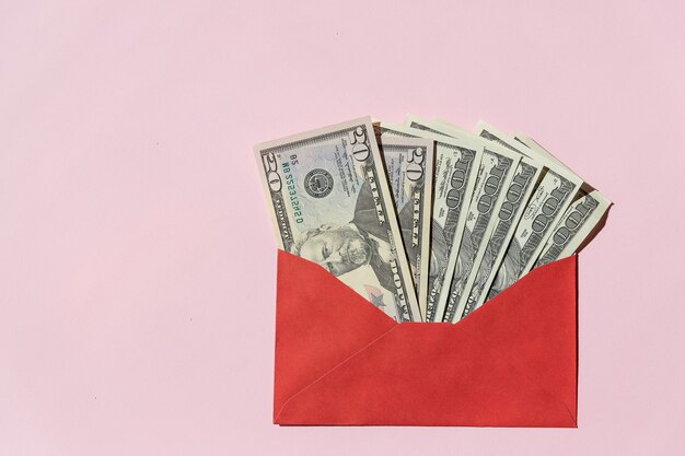 Banknotes of 100 dollars in a red envelope on a pink background.envelope with the inscription savings and dollar bills. Manage your finances and save money concept. Copy space