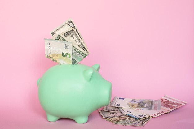 Banknotes of 5 and 10 euros and dollars on a pink background in a piggy bank