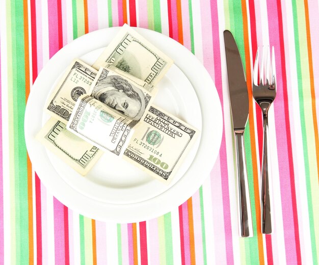 Banknotes on the plate on striped tablecloth closeup
