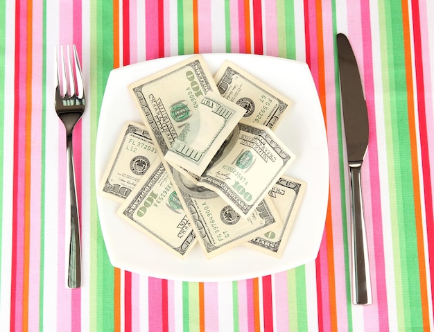 Banknotes on the plate on striped tablecloth closeup