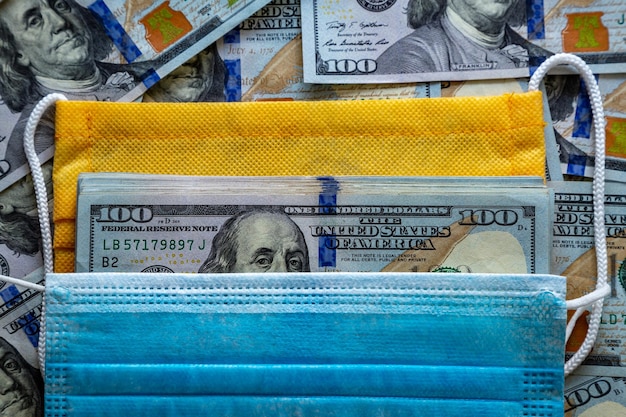 Banknotes of the United States of America and a protective mask against the virus World economic crisis associated with coronovirus