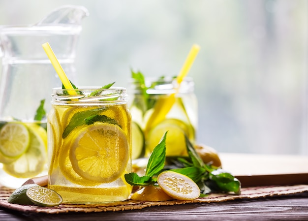 Banks and a jug with cold lemonade and ingredients on a wooden