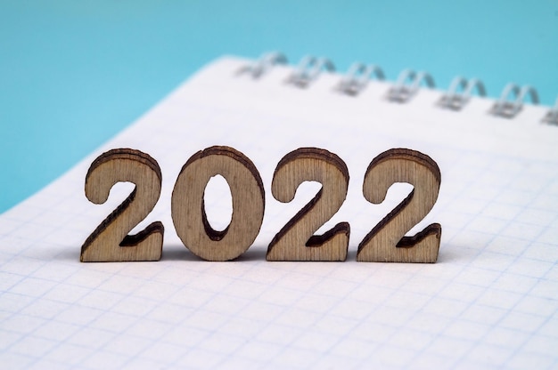 Foto banner 2022 en notepad figuur 2022 op blauwe achtergrond houten figuren op blauwe agtergrond nieuwjaarskalender