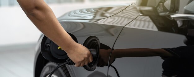 Banner of closeup asian technician hand is charging the electric car or ev in service center