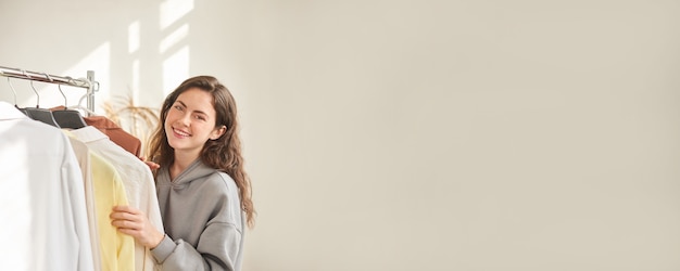 Banner for clothes shop. woman in the store chooses clothes.\
seller hangs clothes on hangers. shopping content