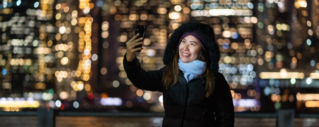 셀카용 스마트 휴대전화를 사용하는 겨울 정장을 입은 아시아 여성의 배너 및 표지
