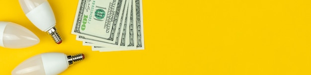 Banner energy saving. led light bulbs and money. yellow background, banner, flat lay photo