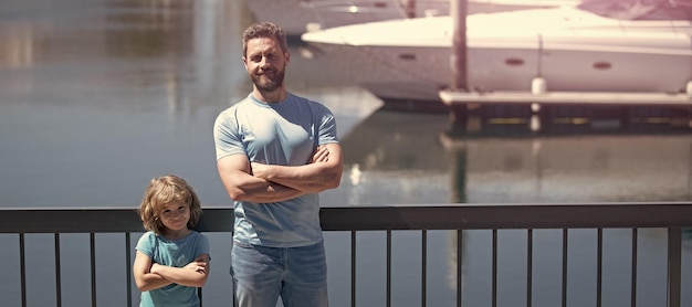 Banner of father man and son child stand on quay railing keeping arms crossed with confidence fathers day