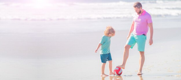 父と息子の旗はビーチでサッカーまたはサッカーをします父と息子はボールサッカーで夏のビーチでサッカーをします