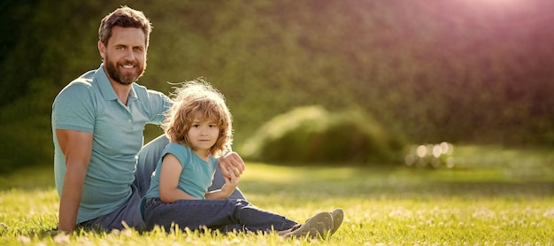 夏の公園で父と息子のバナー屋外幸せな家族の肖像画父と息子の男の子の夏の公園でリラックス緑の草家族の愛