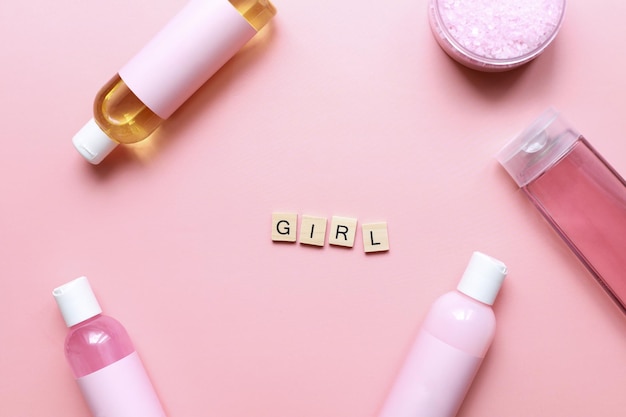 Banner Flat lay word girl from wooden letters on a pink background Bottles mockup Spa jars Girl care beauty routine