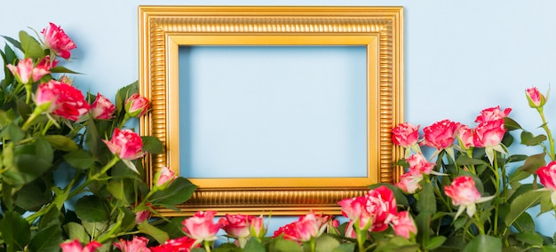 banner golden frame empty blank picture surrounded spray red roses on blue background.