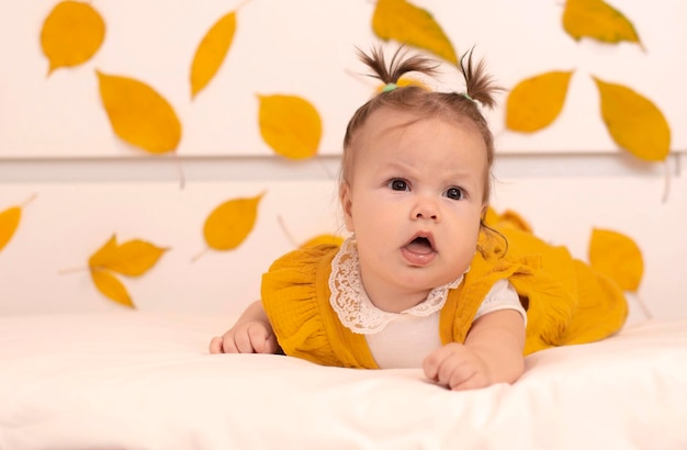 Photo banner a happy child in a bright orange suit lying on his stomach on an autumn background a smiling baby a child of six months a healthy newborn autumn mood concept of children's goods