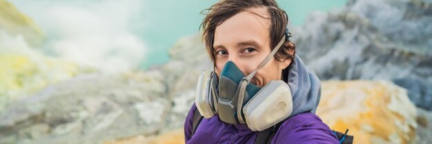 Banner lang formaat jongeman toerist maakt een selfie staande aan de rand van de krater van de ijen