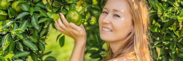 Banner lang formaat portret van aantrekkelijke boerenvrouw oogst sinaasappel in biologische boerderij vrolijk