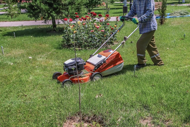 バナー芝刈り機の男が裏庭で草を刈る庭の手入れのための農業機械