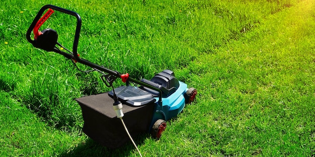 Banner lawnmower machine electric trimming green grass Lawn cutting with sunlight