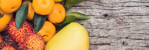 BANNER, Long Format Colorful fruits on the white wooden table, Bananas, carambola, mango, papaya, mandarin, rambutan, pamela, copy space