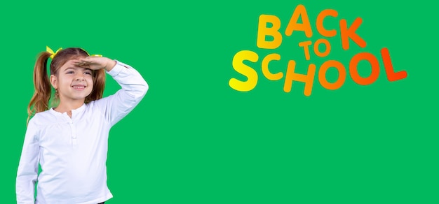 Banner, long format. Pretty school aged girl looks into the distance on a green background, holding her hand on her forehead. Side space. High quality photo