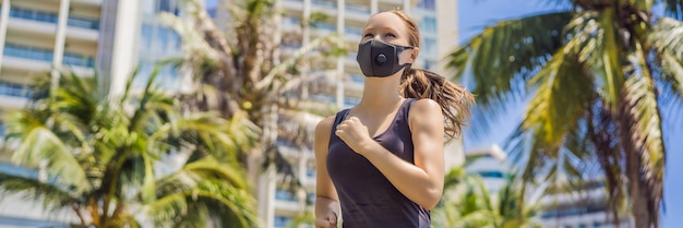 의료 마스크를 착용한 여성 달리기 선수가 도시의 배경에 달리고 있습니다.