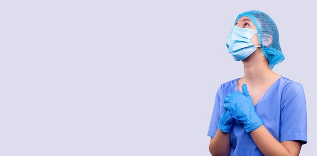 banner long format young medical sister prays for health of patients medical mask stop coronavirus grey background