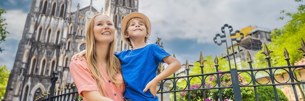 Photo banner long format young mom and son tourists on background of st josephs cathedral in hanoi vietnam reopens after coronavirus quarantine covid 19