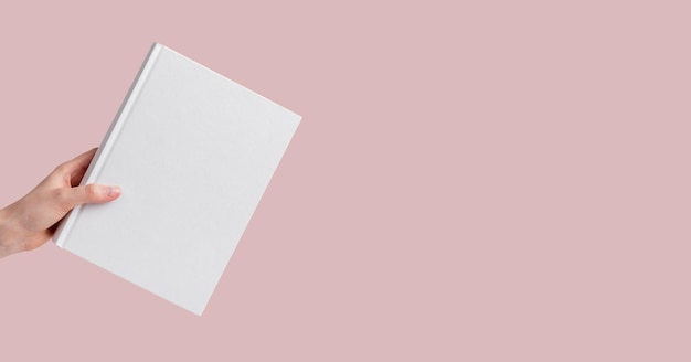 Banner met hand met boekmodel op roze pastelachtergrond Onderwijslezingsonderzoek uitvoeren om kennisconcept te krijgen Kopieer ruimte