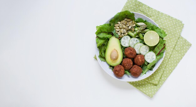 Banner met verse vegetarische kom met falafel avocado komkommer asperges limoen vlas en pompoenpitten en mangold salade bladeren op een witte achtergrond gezonde schotel met kopie ruimte plaats voor tekst