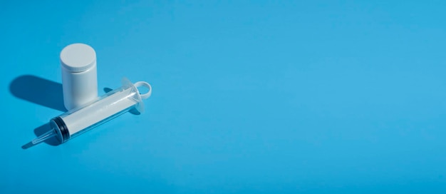 Foto banner.pills, spuit voor een katheter op een blauwe medische achtergrond. close-up, bovenaanzicht. medische spuit, tube met vitamines