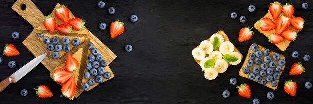 Banner Sandwiches met pindakaas en fruit op de zwarte houten achtergrond Bovenaanzicht Kopieer de ruimte