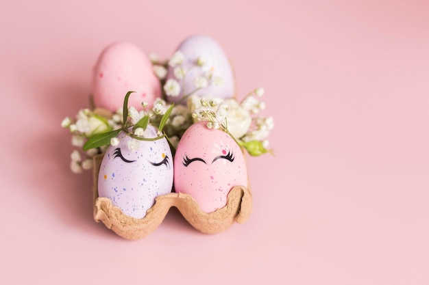 Photo banner stylish easter pink and liliac eggs with cute faces in floral wreath crowns in carton tray on pink background easter decorations and gift happy easter concept copy space isolated