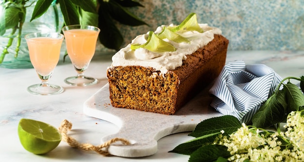 Banner of summer sweet loaf cake on a table with flowers and a drink in glasses with coconut cream and lime dessert for brunch or morning breakfast