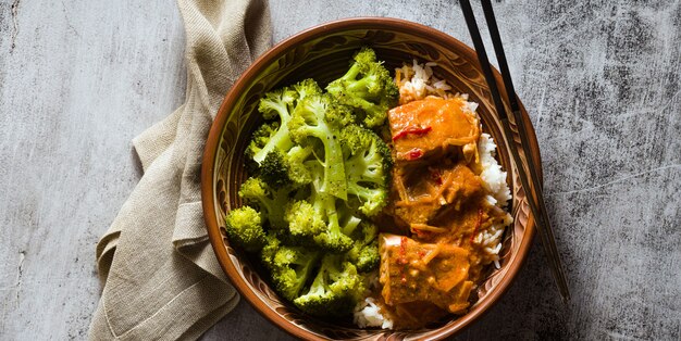 Banner of Thai salmon dish in coconut sauce with fresh broccoli and rice in a clay bowl with chopsticks