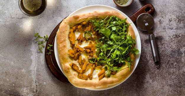 Banner of traditional Italian white pizza with taleggio cheese, caramelized pumpkin and arugula on the table