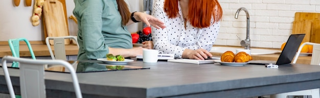 Banner two women are enthusiastically talking in the kitchen in the home interior female business