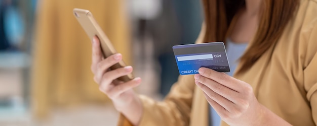 Banner van Aziatische vrouw die creditcard met mobiele telefoon voor online het winkelen in warenhuis met behulp van