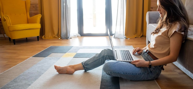 Banner van een vrouw die op een laptop werkt terwijl ze op de grond zit in een modern, stijlvol minimalistisch interieur