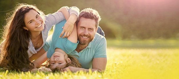 Foto banner van gelukkige familie liggend op gras jonge moeder en vader met kind zoon in het park samen rusten op het groene gras familie plezier buiten in de zomer