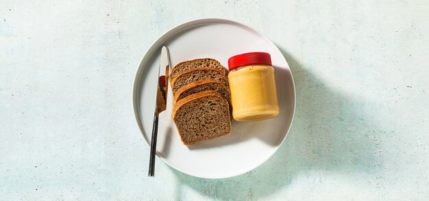 Banner van pindakaas in een pot en volkorenbrood met een mes op tafel.