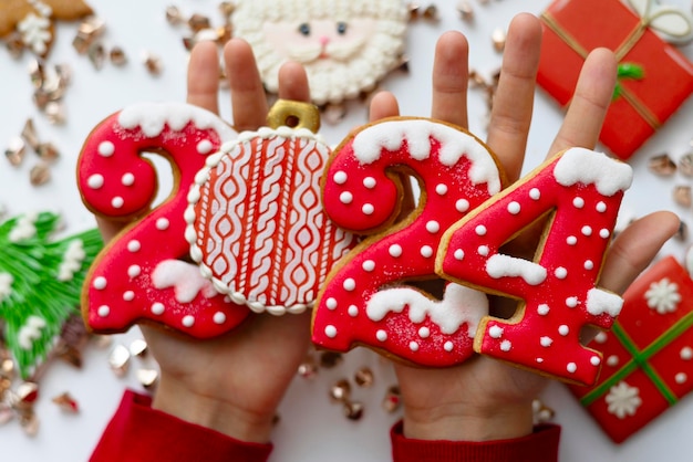 Foto banner voor kerstmis en nieuwjaar peperkoekkoekjes nummers 2024 op witte achtergrond in kinderhanden